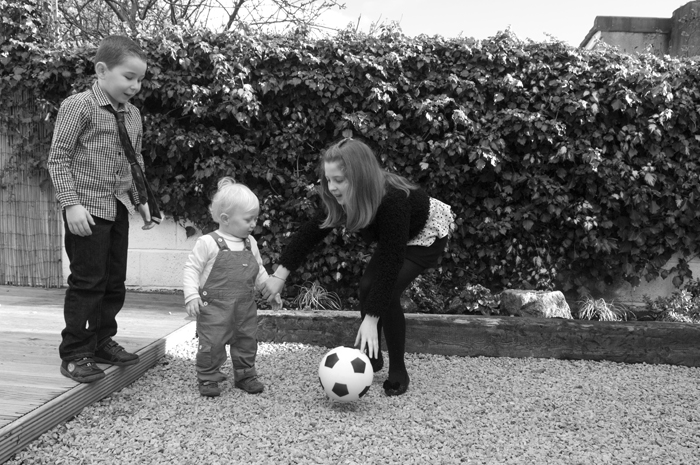Portrait of children playing with a football in the back garden