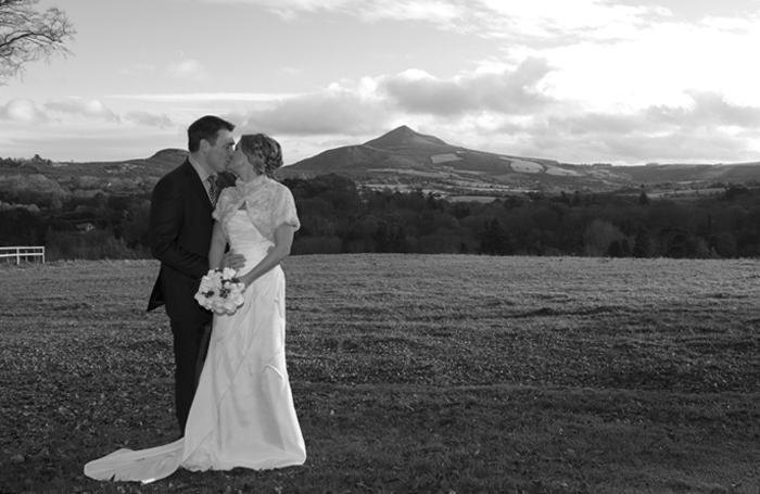 The bride and groom pose for a wedding portrait by The Sugarloaf Mountain in wicklow