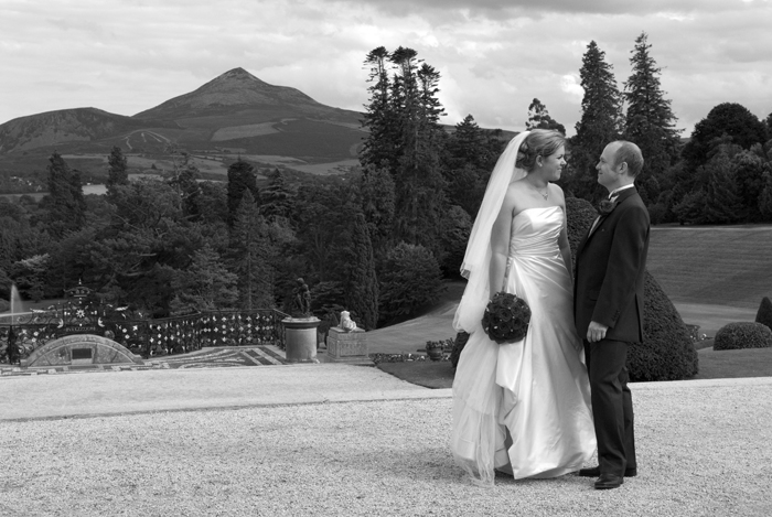  The bride and groom stand for a wedding photograph in the grounds of Powerscourt Estate with the Sugarloaf Mountain in the background. 