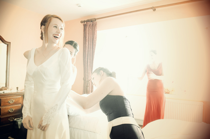 The bride is helped into her wedding dress by the bridesmaids in preparation to be married in a country church in Sneem on The Ring of Kerry